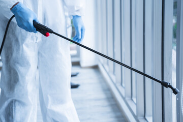Man in virus protective suite and mask spraying alcohol cleaning covid19 infected area, Virus...