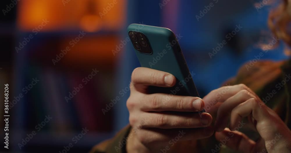 Wall mural close up view of males hands scrolling and touching screen while holding smartphone. young guy using