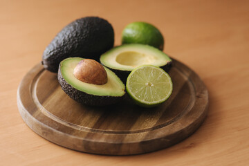 Avocado and lime halves on wooden board. Vegetarian food concept