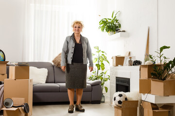 Happy excited mature retired middle aged woman standing in modern living room interior alone with...