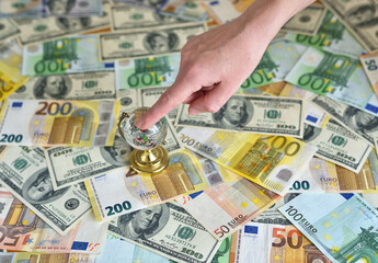 little globe on the table with money. female hand indicates a place on the map