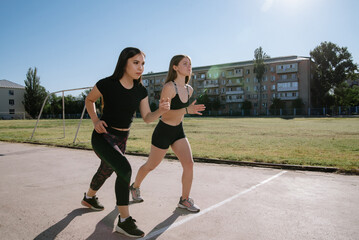 Fototapeta premium Two athletes at the starting position in the stadium. Athletic girls run in the stadium