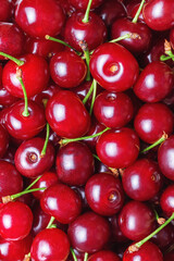 Top view of a ripe juicy sweet shiny cherry with green sprigs. Abstract fruit food texture background with copy space.