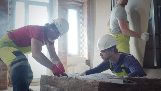 Workers insulating a room wall with mineral rock wool
