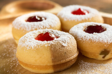 tasty donuts with blueberry and strawberry jam sprinkle with icing sugar put on wooden dish. Hanukkah celebration (Festival of lights). Close up photography.