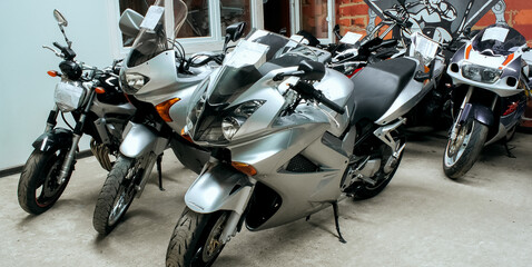 Gray sports beautiful bikes in a motor show. Many motorcycles parked in a store. Sale of motorbikes in the cabin. Exhibition garage equipment. Banner for web site