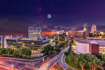 Naklejka premium Sandton City skyline lit up at night with moon and stars in the sky