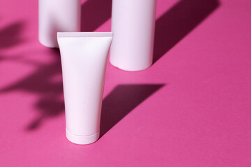 Skincare products containers on bright pink background