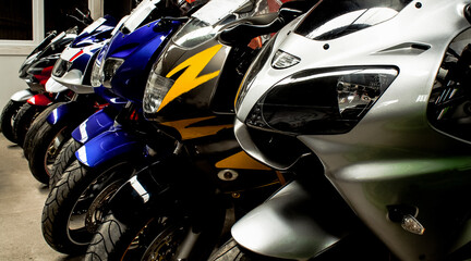 Colored sports, road beautiful bikes in a motor show, close up. Many motorcycles parked in a store. Sale of used cruise motorbikes in the cabin. Showroom equipment in the garage. Banner for web site