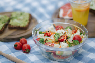 Fresh vegan salad outdoors on blue checkered napkin. Vegan food concept outdoor