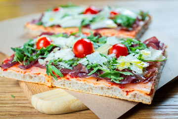 pizza with cherry tomatoes, parmesan cheese, arugula and smoked ham