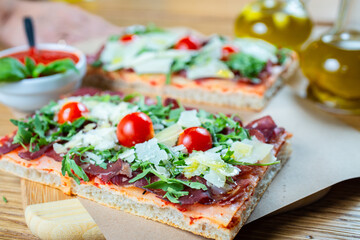 pizza with cherry tomatoes, parmesan cheese, arugula and smoked ham