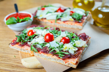 pizza with cherry tomatoes, parmesan cheese, arugula and smoked ham