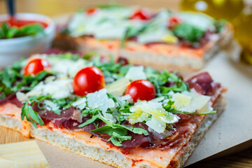 pizza with cherry tomatoes, parmesan cheese, arugula and smoked ham
