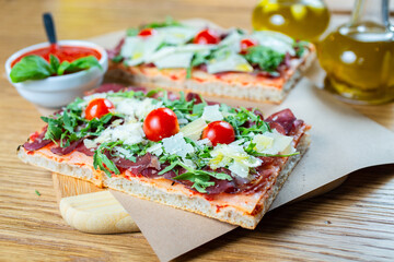 pizza with cherry tomatoes, parmesan cheese, arugula and smoked ham