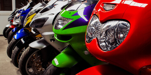 Colored sports, road beautiful bikes in a motor show, close up. Many motorcycles parked in a store. Sale of used cruise motorbikes in the cabin. Showroom equipment in the garage. Banner for web site