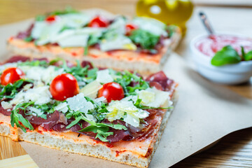 pizza with cherry tomatoes, parmesan cheese, arugula and smoked ham