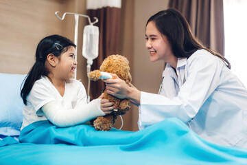 Asian smiling woman doctor service help support discussing and consulting talk to little girl patient give teddy bear and check up information in hospital © Art_Photo
