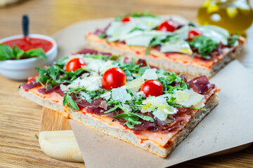 pizza with cherry tomatoes, parmesan cheese, arugula and smoked ham