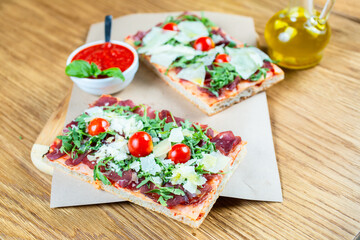 pizza with cherry tomatoes, parmesan cheese, arugula and smoked ham