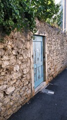 Błękitne drewniane drzwi w kamiennym murze