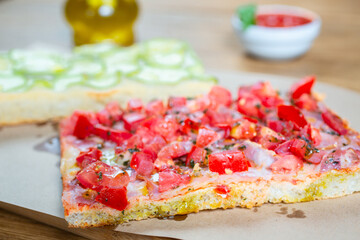 Pizza with tomato, ham, pesto and zucchini