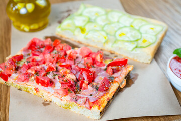 Pizza with tomato, ham, pesto and zucchini