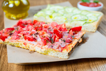 Pizza with tomato, ham, pesto and zucchini