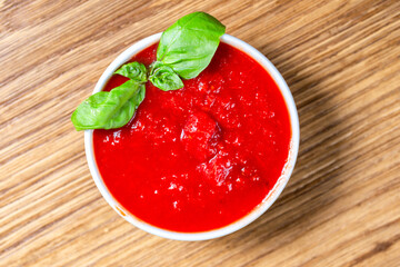 tomato sauce with fresh basil on a wooden background