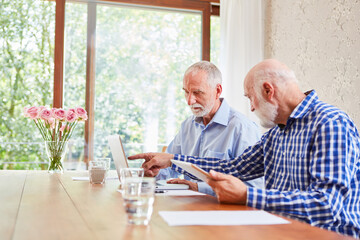 Zwei Senioren mit Laptop und Tablet Computer