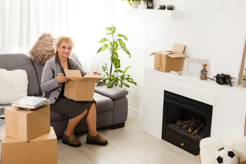 Happy excited mature retired middle aged woman standing in modern living room interior alone with...