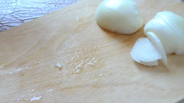 Girl chopping a onion with a knife on the cutting board. preparing to cook chicken soup or vegetable stew or salad
