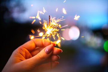 Woman hands holding sparkler, evening time.
