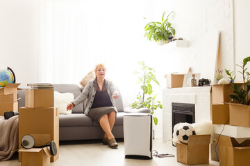 Fototapeta premium elderly woman next to an air purifier moving to a new apartment
