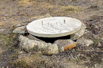 dilapidated well of underground utilities is covered with a concrete cover for safety, selective focus