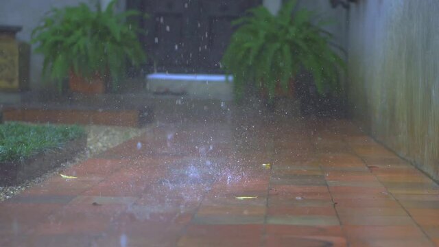 Rainwater falling from the roof of the house to the corridor covered with red ib