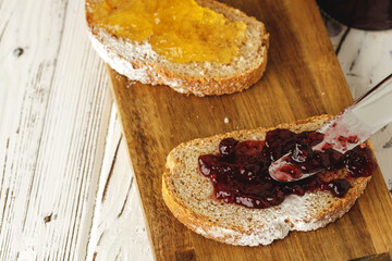 Slice of bread covered with fruit jam on wooden board