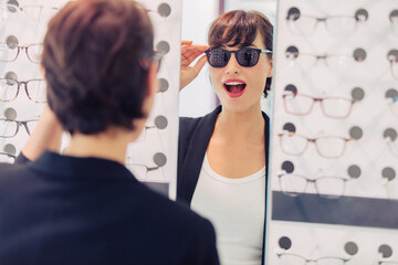 a woman tries on sunglasses in a glasses store