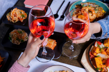 Cheers with wine glasses and asian food