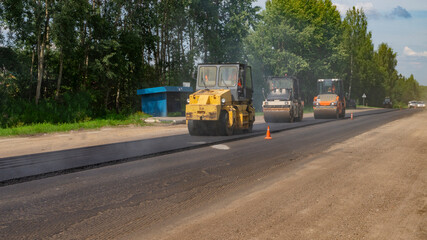 Fototapeta na wymiar Rollers paving asphalt. Road repair works on the suburb highway