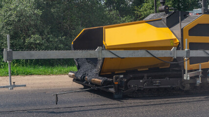 Close-up asphalt paver machinery. Road repair works on the suburb highway