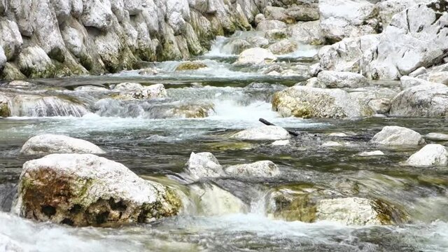Boulders in Sava Bohinjka river with clean water flowing in Slovenia taken with motion blur effect
