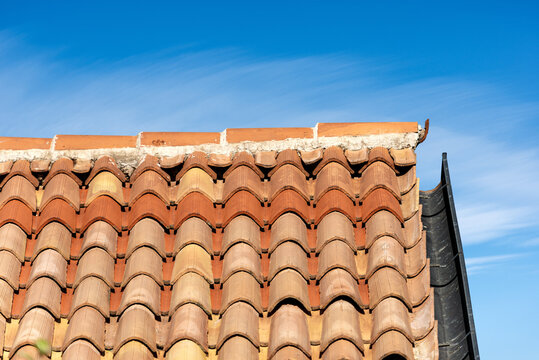 Pantiles. Closeup of a roof with terracotta tiles (Coppo in Italian language) and gutter on a blue sky with clouds. Veneto, Italy, Europe