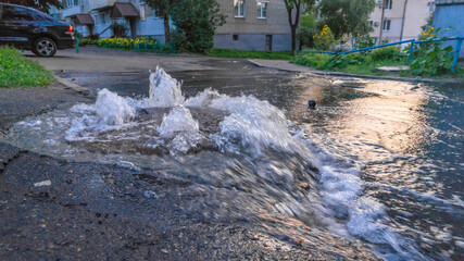 Dirty sewage water flows fountain on road from sewer manhole