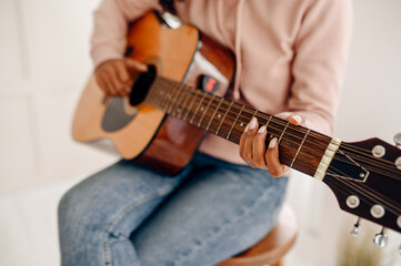 Fototapeta na wymiar Woman play the guitar at home, closeup view