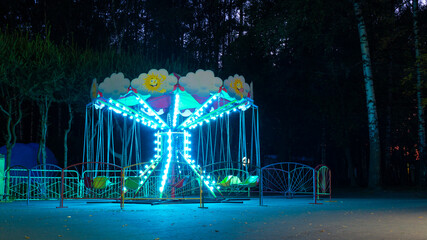 Luminous children's attraction in the city park in the late evening