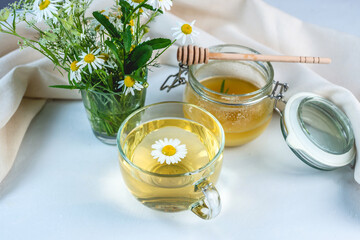 Transparent сup of hot chamomile tea and honey. Concept of a healthy soothing herbal drink after a...