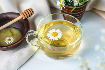 Transparent сup of hot chamomile tea and honey. Concept of a healthy soothing herbal drink after a hard day or in the morning