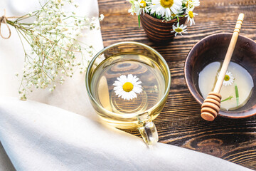 Transparent сup of hot chamomile tea and honey. Concept of a healthy soothing herbal drink after a...
