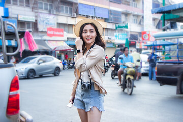 Fototapeta premium asia female tourists wearing hat holding camera and smartphone take photo vlog live. Beautiful woman take taxi boat visiting Damnoen Saduak floating market,Ratchaburi.